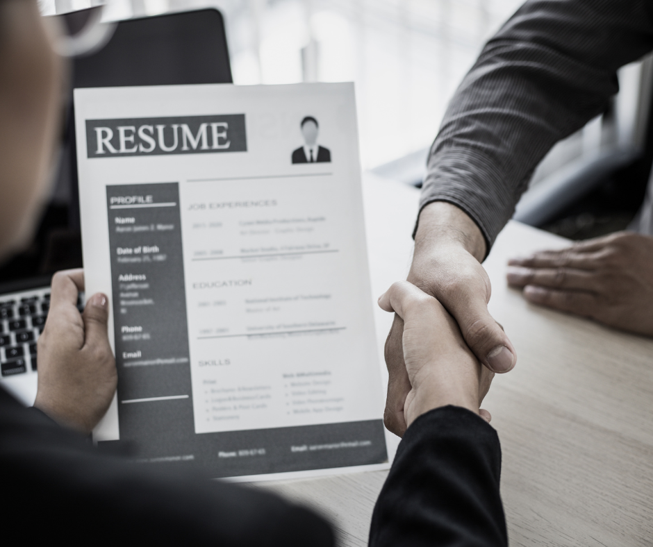A resume and a recruiter and a candidate shaking hands
