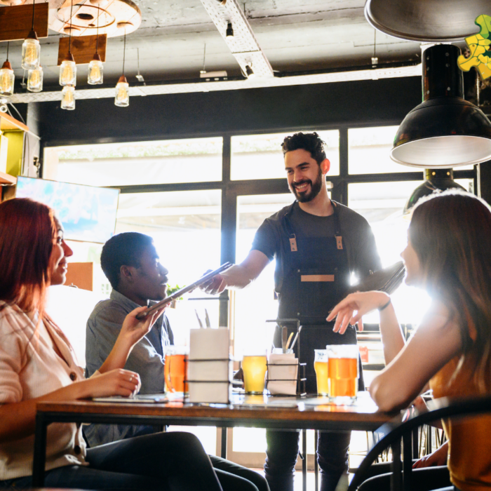 A Waiter talking with clients seating at a table